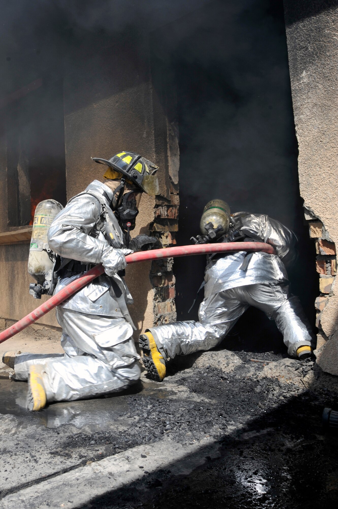 A 447th Expeditionary Civil Engineer Squadron and Baghdad International Airport firefighters enter a building during live burn training, Aug. 9, 2010, at BIAP, Iraq. Firefighters from the 447th ECES, BIAP and Iraqi air force, frequently train in structural firefighting, to improve their skills. ( U.S. Air Force photo by Senior Airman Perry Aston) (Released)
