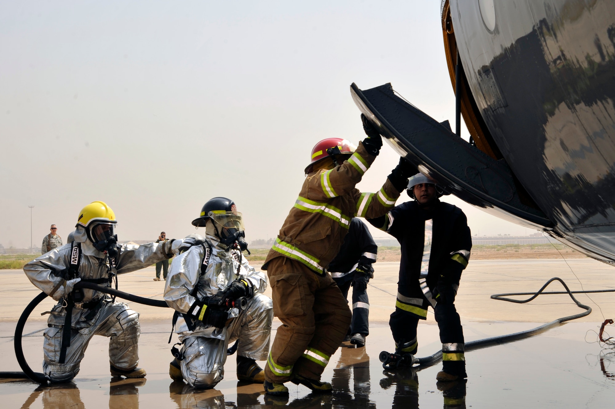 Iraqi air force firefighters open the side hatch on an Iraqi air force C-130 during a simulated aircraft fire Aug. 5, 2010 at New Al Muthana Air Base, Iraq. The firefighters are being trained by 447th Expeditionary Civil Engineer Squadron firefighters in aircraft rescue and firefighting, and structural firefighting. ( U.S. Air Force photo by Senior Airman Perry Aston) (Released)