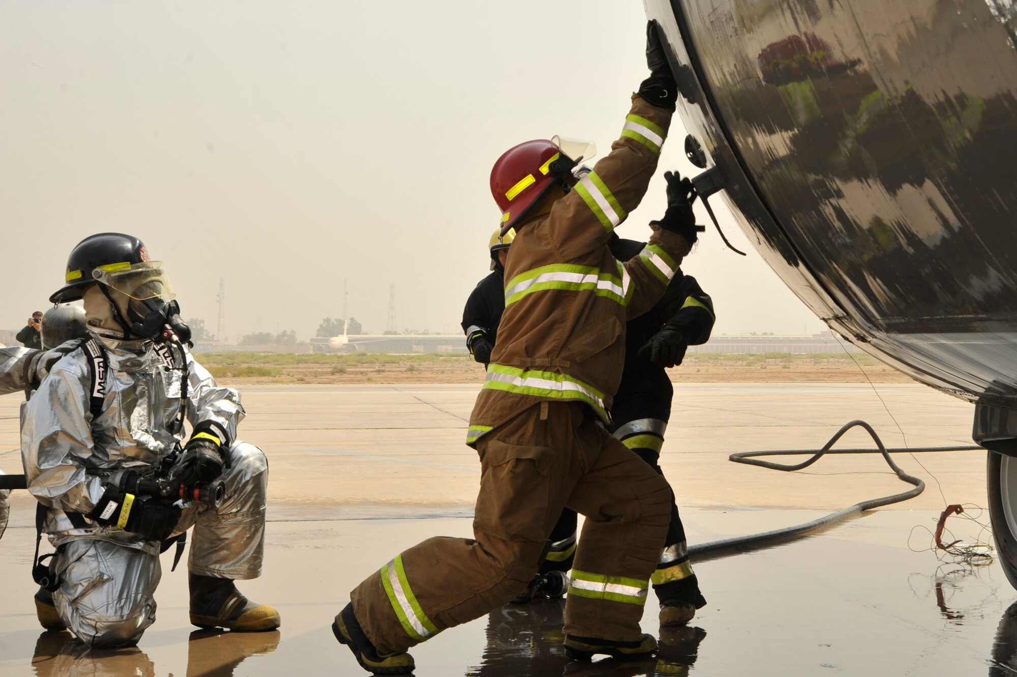 Iraqi air force firefighters open the side hatch on an Iraqi air force C-130 during a simulated aircraft fire Aug. 5, 2010 at New Al Muthana Air Base, Iraq. The firefighters are being trained by 447th Expeditionary Civil Engineer Squadron firefighters in aircraft rescue and firefighting, and structural firefighting. ( U.S. Air Force photo by Senior Airman Perry Aston) (Released)