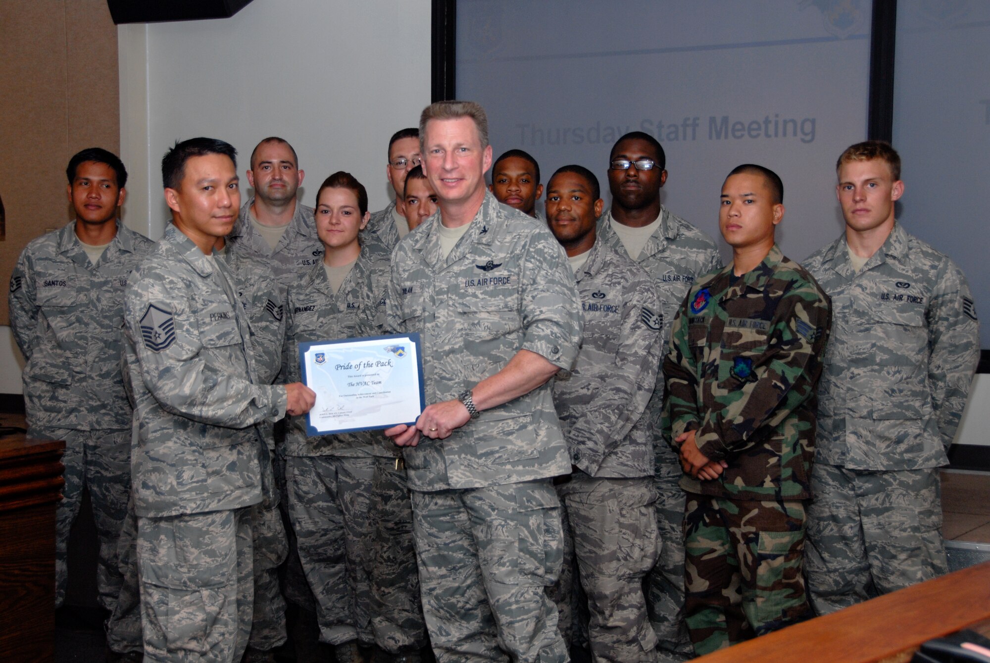 Master Sgt. Nelson Perkins, 8th Civil Engineer Squadron heating, ventilation and air conditioning shop NCO in charge, accepts a Pride of the Pack award from Col. John Dolan, 8th Fighter Wing commander, on behalf of the HVAC shop Aug. 5. According to Senior Master Sgt. Robert Anderson, 8th CES infrastructure superintendent, the shop installed a 330-liters-per-minute pump and reconfigured a chilled water hydraulic system and two 45-ton compressors for the precision measurement equipment laboratory in eight hours, preventing a facility shut-down. The shop rejuvenated a 40-ton chiller at the 8th FW Headquarters back to manufacturer specifications, restoring cooling to the critical command element. The Airmen overhauled a 15-ton chiller at the 8th Operations Support Squadron air traffic control tower, keeping $1.2 million in navigational equipment cool with zero flight delays. They replaced a 14-ton condenser at the 82nd Army Battery Battalion, restoring cooling to 100 personnel. They also repaired a 12-ton air conditioner at the 8th Security Forces Squadron fire arms training center, preventing a $1.5 million simulator from overheating and shutting down. The shop also took ownership of the Collective Protective System base-wide, conducting six of 14 inspections and compiling a comprehensive list of replacement parts and supply stock to provide for Pacific Air Forces fiscal 2010-2011funding, leading the way for 7th Air Force for PACAF-contracted civilians starting 2011.