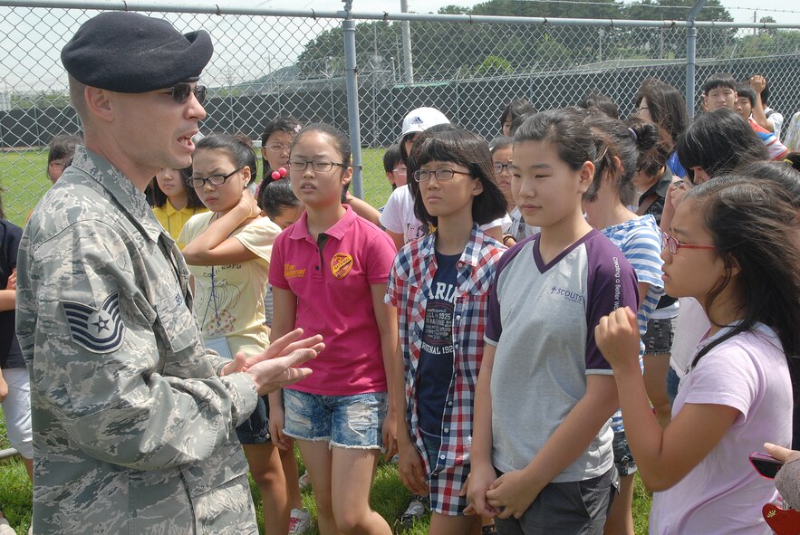 KUNSAN AIR BASE, Republic of Korea -- Tech. Sgt. Andrew Bedell, 8th Security Forces Squadron member, speaks with English camp tour students here Aug. 11 about the vital role in security forces of the military working dog. More than 60 students from several elementary and middle schools in Gunsan city participated in the tour. (U.S. Air Force photo/Senior Airman Ciara Wymbs) 