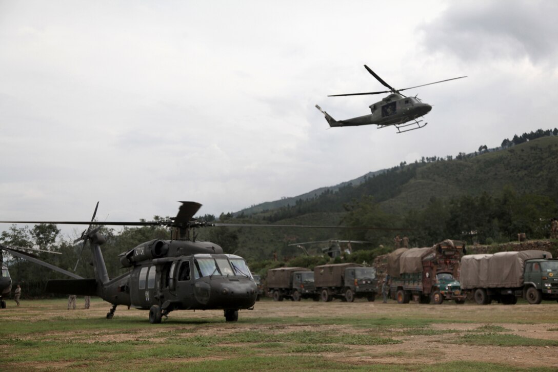 A U.S. Army UH-60 Black Hawk helicopter waits while a UH-1 Huey transport helicopter flies over the landing zone to unload passengers who are being evacuated from the  Swat Valley to Rubicon, Pakistan, Aug. 10, 2010.