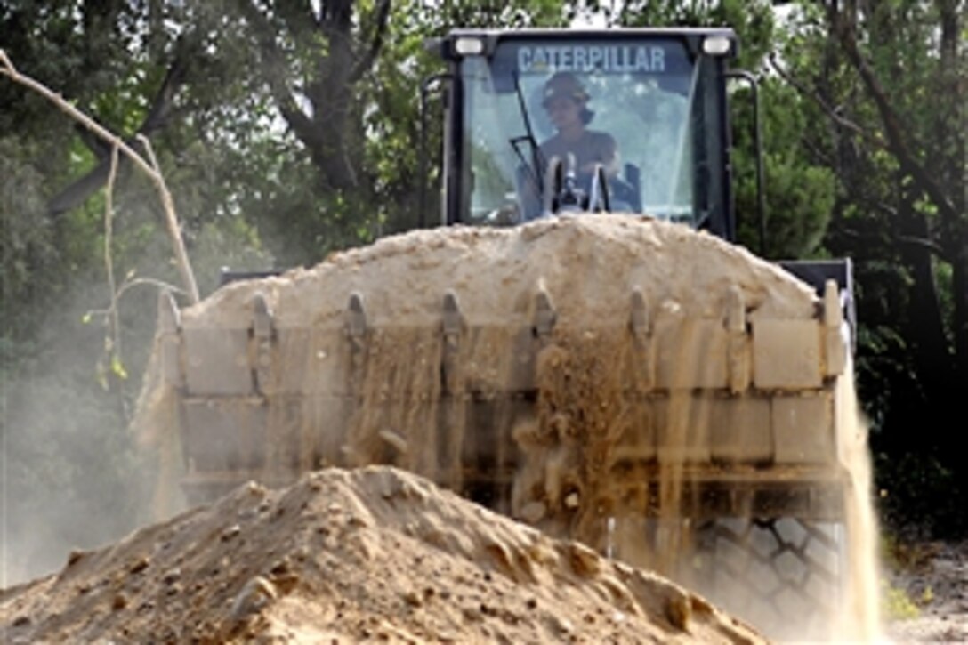 U.S. Navy Seaman Krystal Harris removes fill dirt during a beach parking lot extension project at Naval Station Rota, Spain, Aug. 9, 2010. Harris is an Equipment Operator Constructionman assigned to Naval Mobile Construction Battalion.