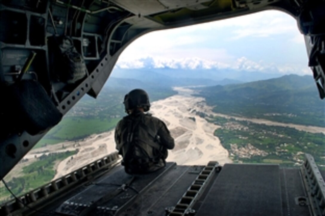 U.S. Army Sgt. Paul Gilman looks out of the back of a CH-47 Chinook helicopter at the water damage while flying over the Swat Valley in Pakistan, Aug. 5, 2010. Gilman is a crew chief assigned to Company B, Task Force Knighthawk, 3rd Combat Aviation Brigade, Task Force Falcon.