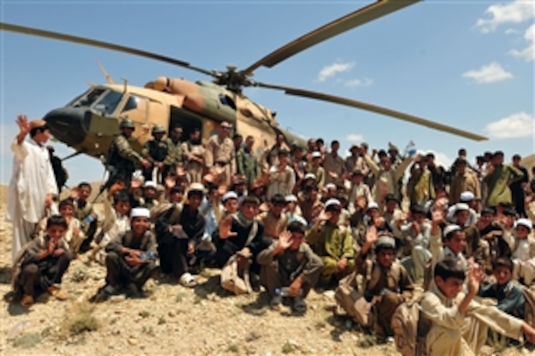 Children from the Chinari Village school outside Kabul, Afghanistan, say goodbye to airmen assigned to the Afghan Air Force 201st Corps, the U.S. Air Force 438th Air Expeditionary Wing and the 438th Air Expeditionary Advisory Wing who delivered school supplies for 600 students, sporting equipment, bedding, a large tent, and an all weather Afghanistan flag, Aug. 9, 2010. 