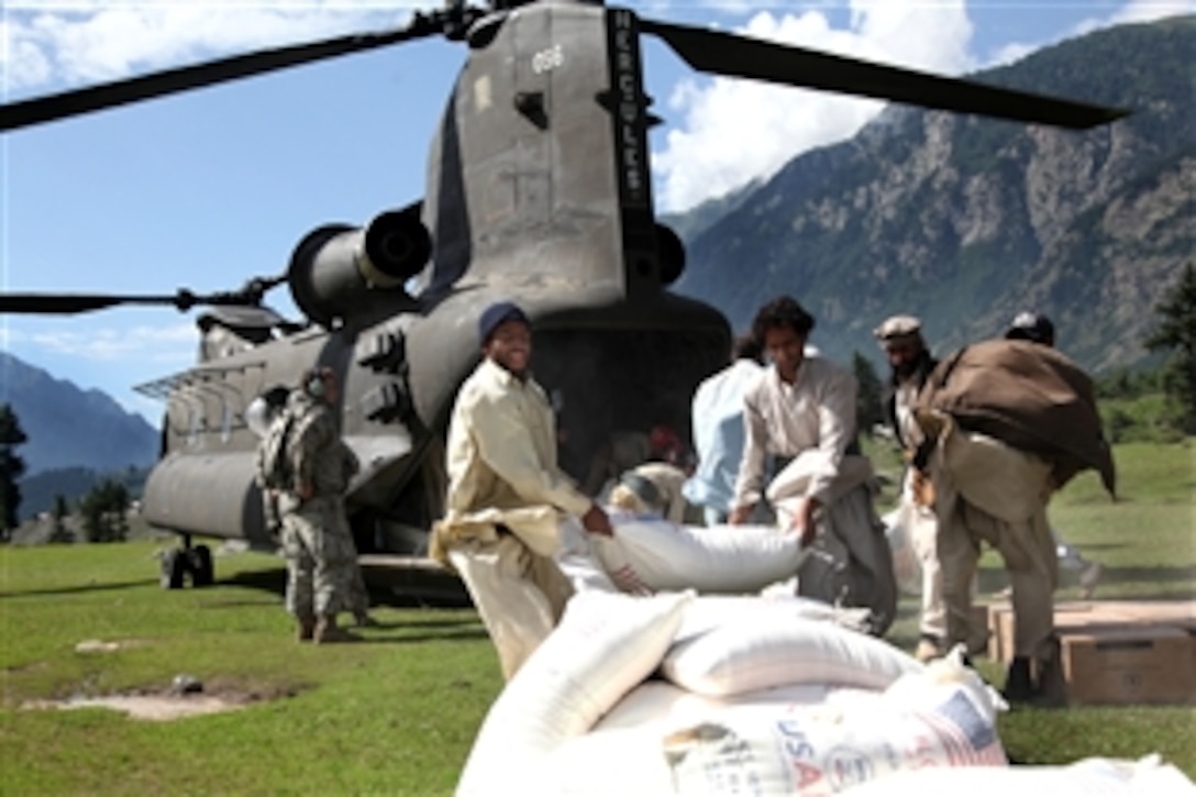 Two Pakistani men throw a bag of flour out the back of a U.S. Army CH-47 Chinook helicopter that has arrived to deliver humanitarian assistance and help with the evacuation of flood victims in the Swat Valley as part of the flood disaster recovery effort in Khyber Pakhtunkhwa province, Pakistan, Aug 11, 2010.