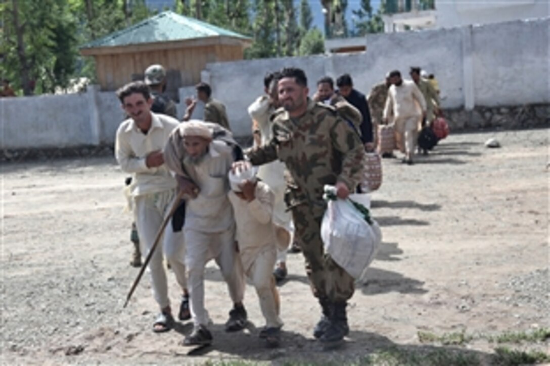 A Pakistani military member assists a man and child during the evacuation process to board a U.S. Army CH-47 Chinook helicopter to the town of Khwazakhela, during the flood recovery effort in Khyber Pakhtunkhwa province, Pakistan, Aug 11, 2010.