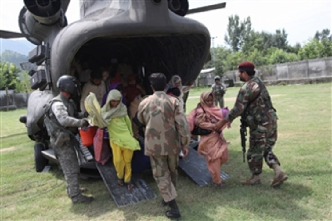 U.S. and Pakistani service members help civilians exit a U.S. Army CH-47 Chinook helicopter in Khwazahkela, Afghanistan, on Aug. 5, 2010.  Humanitarian relief and evacuation missions are being conducted as part of the disaster relief efforts to assist Pakistanis in flood-stricken regions of the nation.  