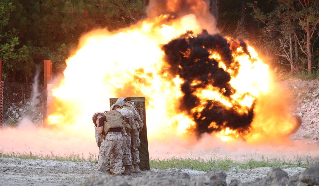 Marines from Company C, 2nd Combat Engineer Battalion, 2nd Marine Division, take cover behind a blast blanket during a live-fire training exercise at the military operations on urban terrain (MOUT) town at Engineer Training Area 3 here August 12. The engineers detonated charges to breach concrete and wooden walls.