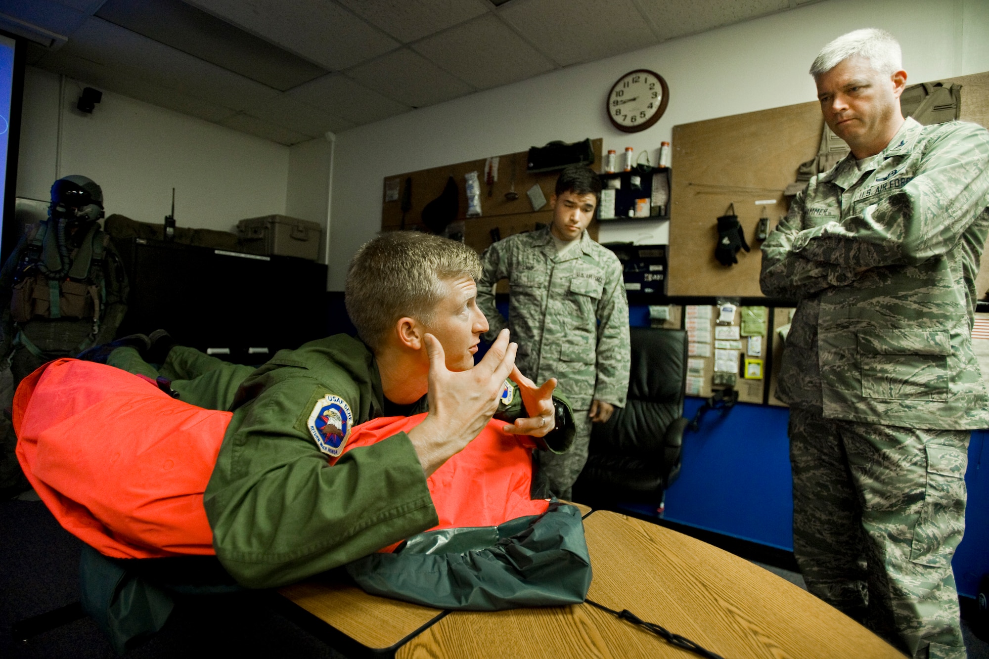 MISAWA AIR BASE, Japan -- Staff Sgt. Benjamin Thomas (left), 35th Operations Support Squadron survival, evasion, resistance and escape specialist, demonstrates proper raft techniques to Staff Sgt. James Land (center), 35th Maintenance Squadron knowledge operations manager, and Col. Van Wimmer (right), 35th Fighter Wing vice commander, Aug. 12 at the 35th OSS headquarters building. The demonstration was part of water survival training, which is customary for pilots. Sergeant Land participated in the class due to a desire to cross train into SERE. (U.S. Air Force photo/Senior Airman Jamal D. Sutter)