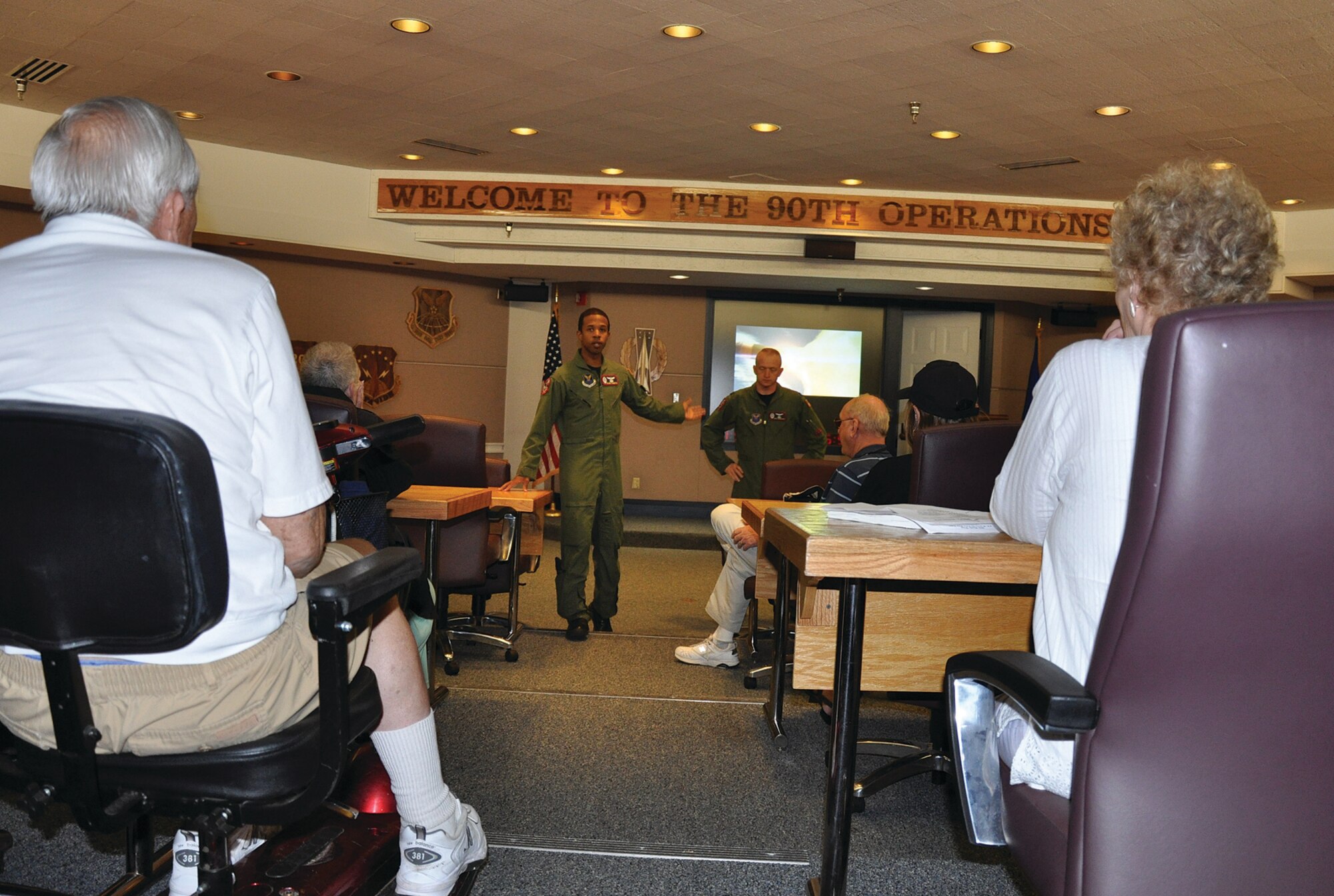 Capts. Palmer Roberts and Richard Morrison, 90th Operations Support Squadron, gives a Missile 101 brief to a group of former Atlas-E crew members who were once stationed here in the pre-departure room on Aug. 3. “It was amazing to see how the weapon has changed and matured, but the mission has still remained the same,” said Col. (ret) Dick Cable, former Atlas missileer. “We are so proud of the people who work this mission. It was an honor to return here.” (U.S. Air Force photo by 1st Lt. Brooke Brzozowske)
