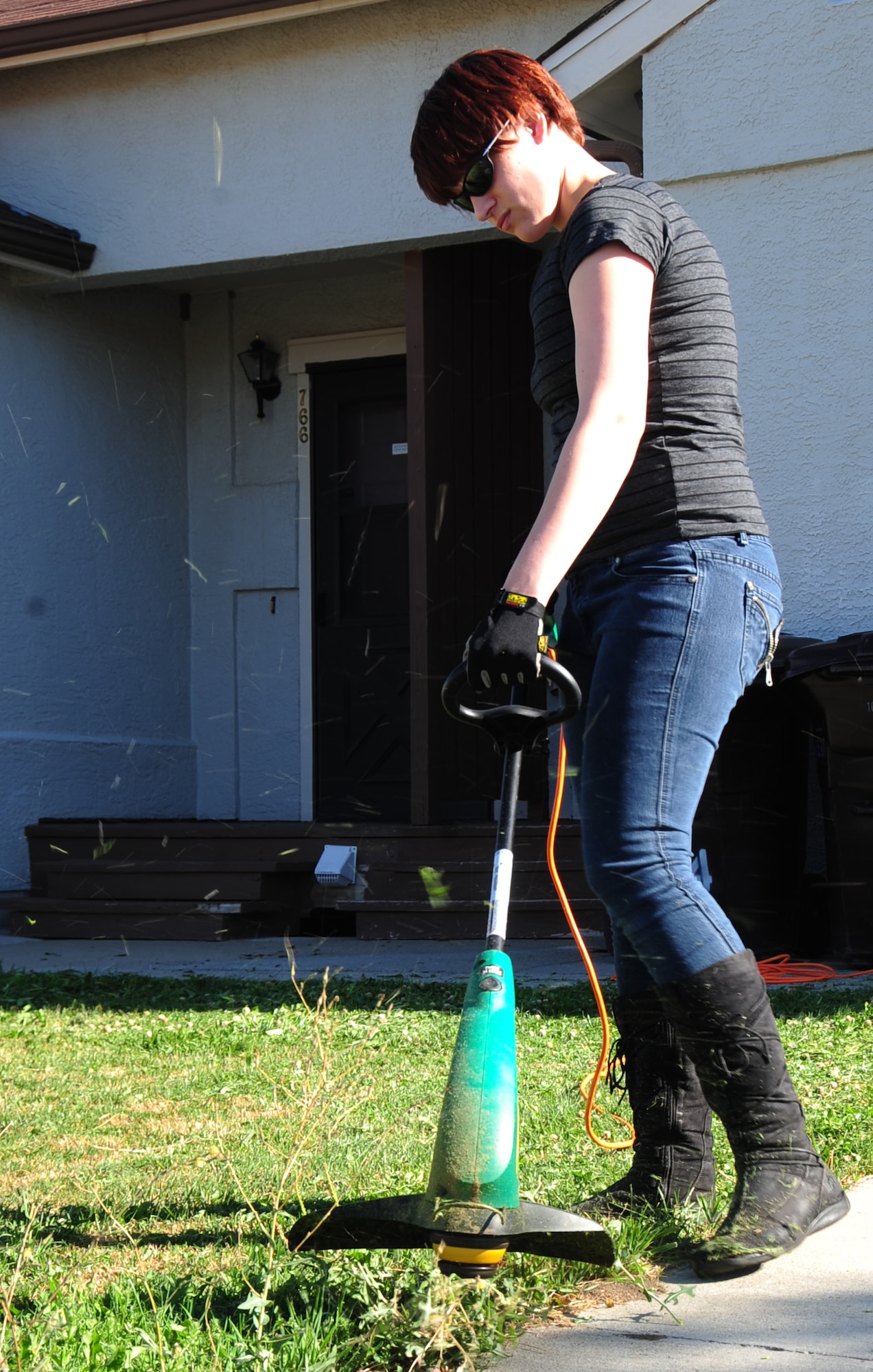 ELLSWORTH AIR FORCE BASE, S.D. -- Airman 1st Class Megan Dix, Air Force Financial Services Center travel technician, cuts the grass using an electric weed-eater, Aug. 12.  Safety glasses, full-fingered gloves and closed-toe shoes should be worn when edging to protect from injuries. (U.S Air Force photo/Airman 1st Class Anthony Sanchelli)
