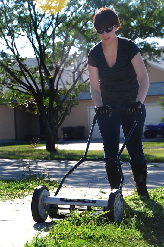ELLSWORTH AIR FORCE BASE, S.D. -- Airman 1st Class Megan Dix, Air Force Financial Services Center travel technician, cuts the grass using a manual push mower, Aug. 12.  While living on base, the yard must be maintained periodically to keep a professional, clean look. (U.S Air Force photo/Airman 1st Class Anthony Sanchelli)
