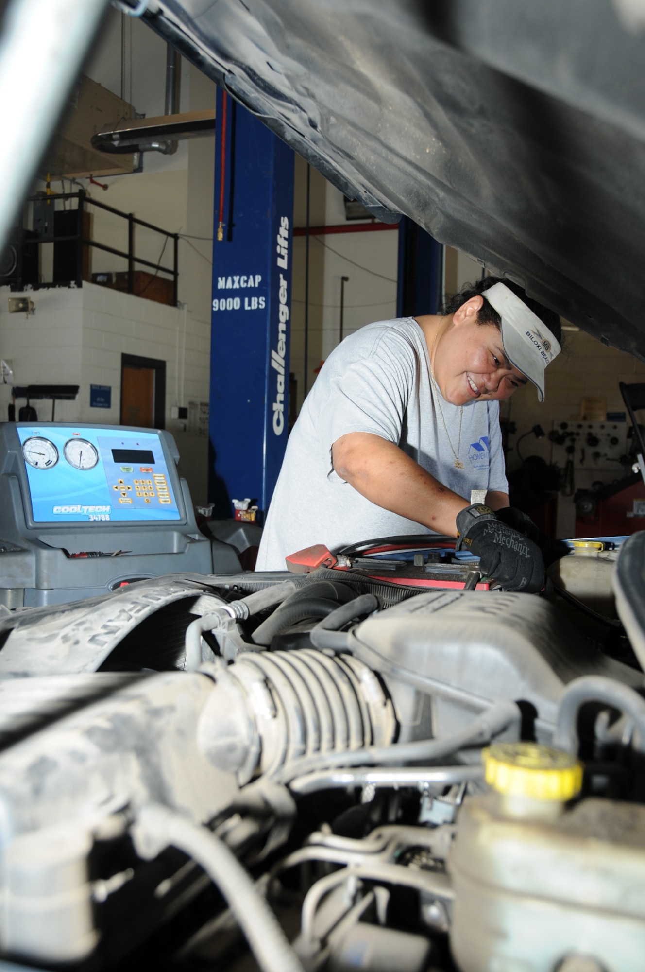 Hobby shop employee Maria Uele helps a customer recharge an air conditioner, a popular request as recent temeratures have risen to near 100 degrees.  (U.S. Air Force photo by Kemberly Groue)