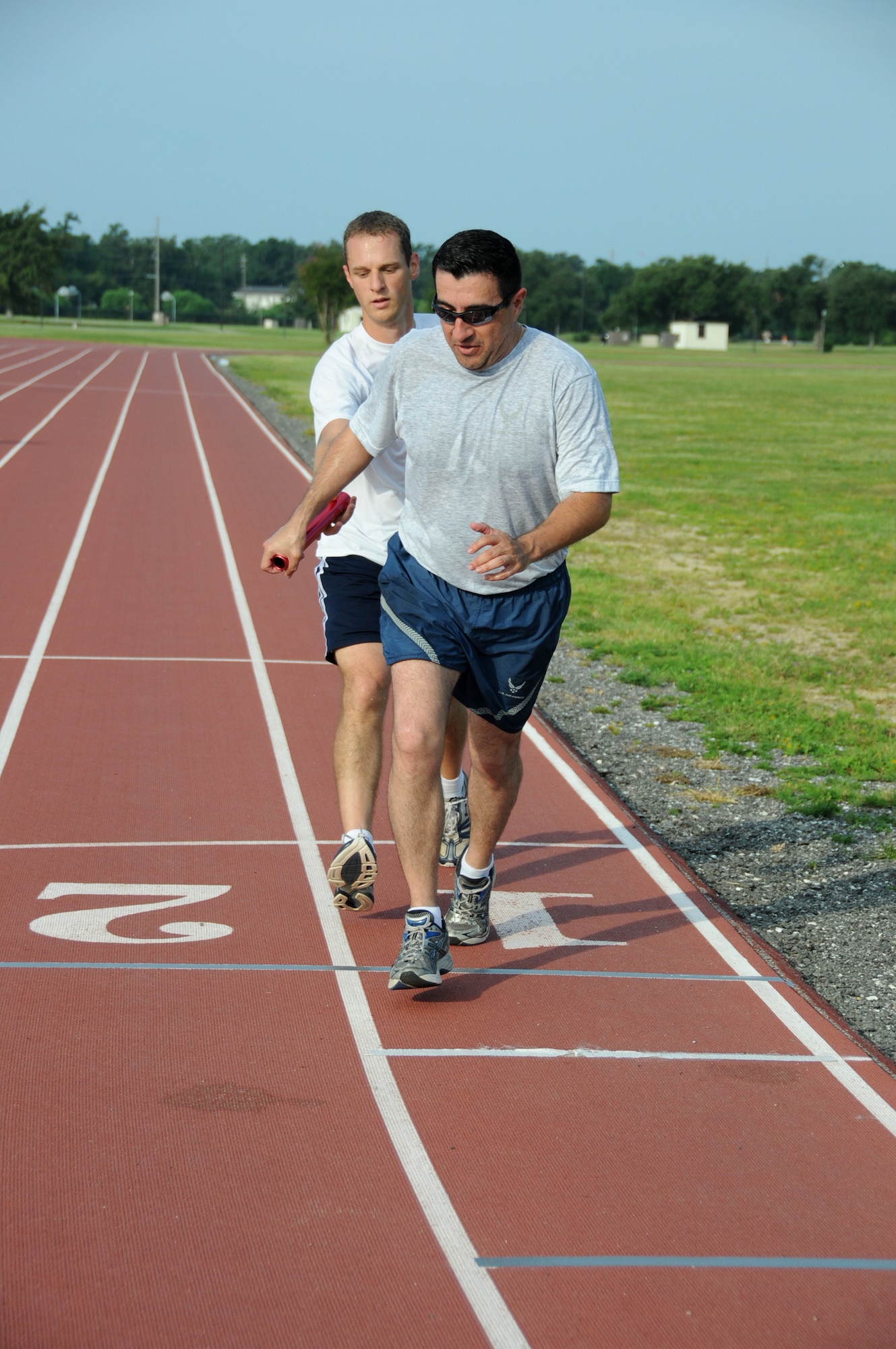 John Capps hands off the baton to Ruben Covos during Saturday’s Dog Day Baton Relay.  Capps is from the legal office and Covos is a chaplain.  Along with their teammates, Michael Wakeley and Justin Thompson from the legal office, they claimed second place in the event.  (U.S. Air Force photo by Kemberly Groue)