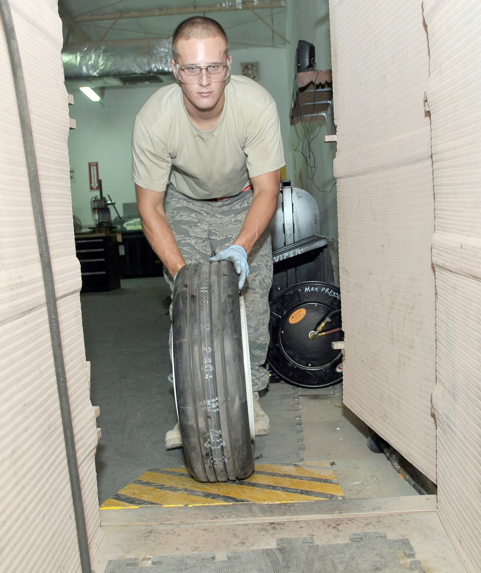 Senior Airman William Davenport pushes a rebuilt aircraft wheel into a tire inflation closet to fill it with nitrogen July 9, 2010, at Joint Base Balad, Iraq. The closet is used to inflate wheels to prevent injury if the wheel explodes while under pressure. Airmen Davenport is a 332 Expeditionary Maintenance Squadron crash recovery, wheel and tire technician. (U.S. Air Force photo/Staff Sgt. Phillip Butterfield)