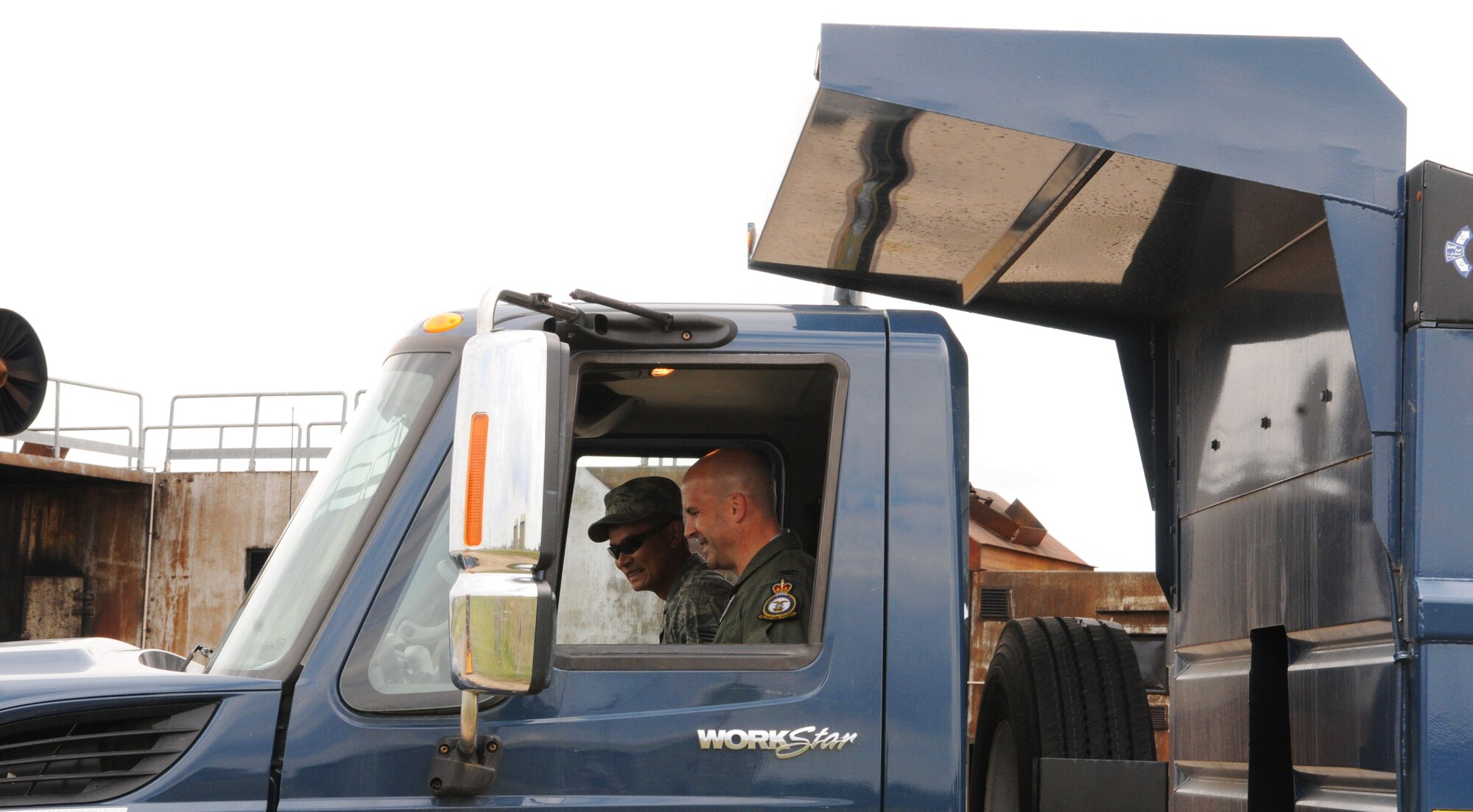 RAF MILDENHALL, England -- Staff Sgt. Ty Bunn, 100th Civil Engineer Squadron (left), teaches the operations of a 10-ton dump truck to Col. Chad Manske, 100th Air Refueling Wing commander, at the live-fire training area Aug. 11. Meeting Airmen from across the base and seeing the expertise they require to perform their duties gives leadership a better understanding of operations on a daily basis. (U.S. Air Force photo/Staff Sgt. Thomas Trower) 