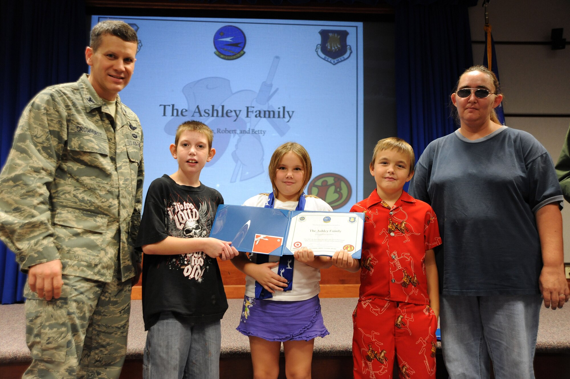 Col. Jamie Crowhurst, 22nd Air Refueling Wing commander, presents scholarships to Jonathan Ashley, 11, Coleman Elementary school student, Betty Ashley, 7,  Calvin Elementary School student, and Robert Ashley, 8,  Calvin Elementary School student, with their mother Mary Ashley during the 2nd Annual Big Brothers Big Sisters Scholarship presentation Aug. 11, 2010 McConnell Air Force Base, Kan. The 349th Air Refueling Squadron raised money to help underprivileged youth from the local area purchase school supplies for the upcoming school year.  Members from the squadron will accompany the recipients and BBBS on a shopping trip to purchase the supplies. (U.S. Air Force photo/Senior Airman Courtney Witt)