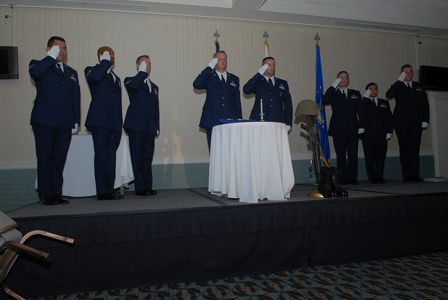 KUNSAN AIR BASE, Republic of Korea -- Members of the Kunsan Airman Leadership Class 10-K honor guard salute the flag placed at the Prisoner of War/Missing In Action table during the ALS Class 10-K graduation here Aug. 6. The class was the first at Kunsan in six years. (U.S. Air Force photo/Senior Airman Roy Lynch)