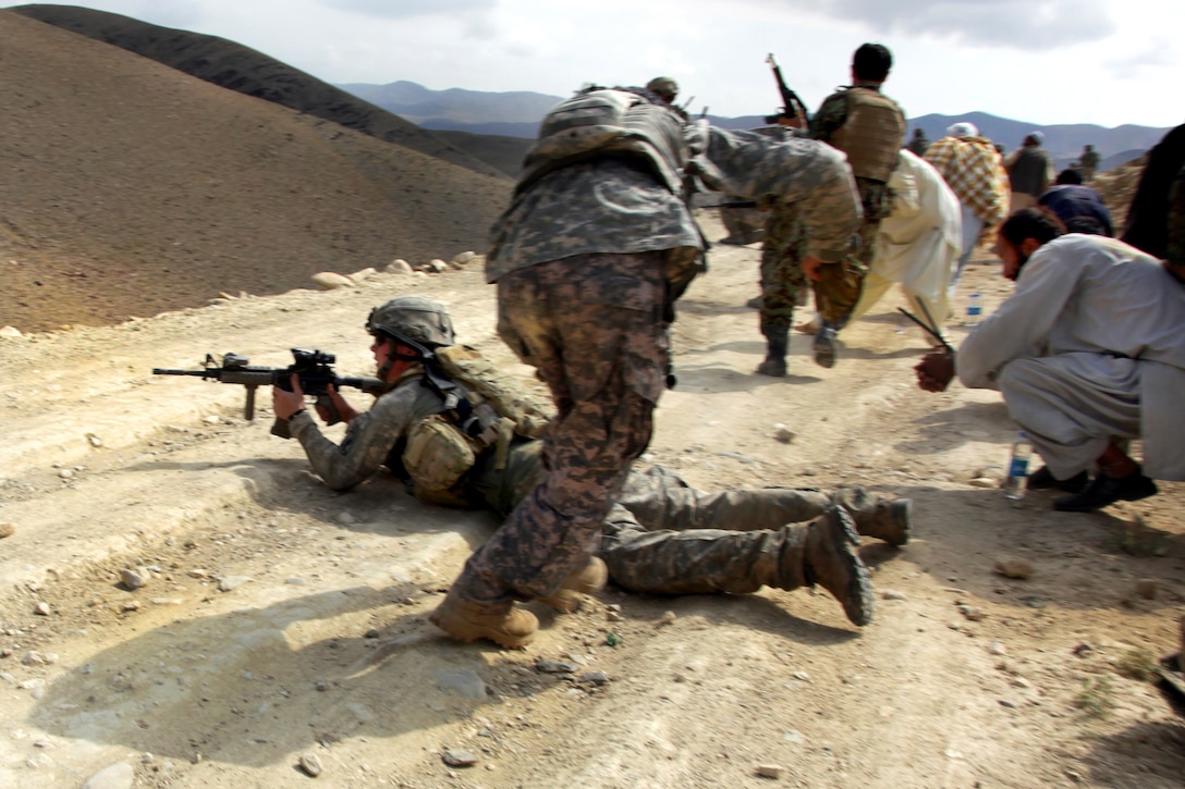 A U.S. Army soldier, left, returns fire while Afghan National Army soldiers, and detainees seek cover during a firefight with enemy forces in Shekhabad Valley, Wardak province, Afghanistan, Aug. 9, 2010. The U.S. soldiers are assigned to the 173rd Airborne Brigade Combat Team.