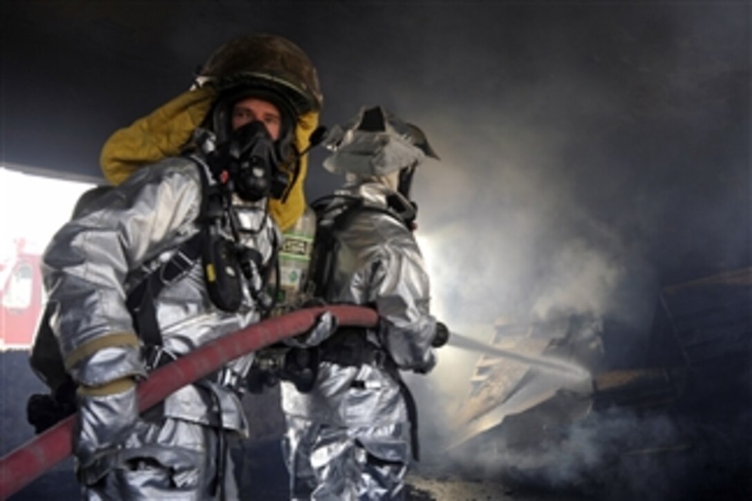 Firefighters from the 447th Expeditionary Civil Engineer Squadron extinguish a fire in a training room during live-burn training at Baghdad International Airport, Iraq, on Aug. 9, 2010.  Firefighters from the squadron, the airport and the Iraqi air force frequently train on structural firefighting to improve their skills.  