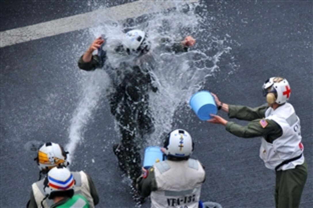 U.S. Navy Capt. Alton E. Ross Jr. receives a soaking down as he returns to the aircraft carrier USS Abraham Lincoln after an in-flight change of command ceremony in which he was relieved by Navy Capt. John Eden as the commander of Carrier Air Wing 2 in the Pacific Ocean, Aug. 7, 2010. 