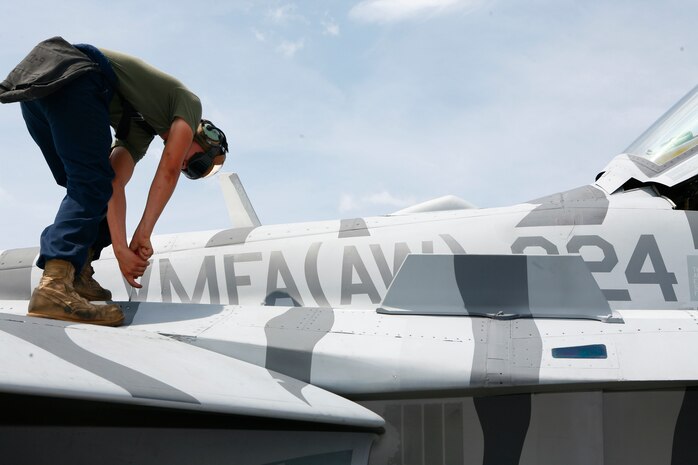Lance Cpl. David Strawder, a Marine All-Weather Fighter Attack Squadron 224 powerline plane captain, tightens a fastener on the squadron’s flag plane during a take off inspection here Aug. 12. The tactical tiger-striping paint on the squadron’s flag plane is unique and recognized across the world to signify 224’s presence.