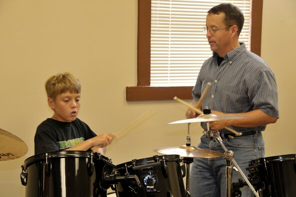 In 2008, (from right) Col. James Jolliffe, the special assistant to the center commander, provided drumming instruction to James Kennedy, the son of Maj. Jim Kennedy, AEDC’s former Judge Advocate General. Colonel Jolliffe said he has been most influenced by the drumming of Buddy Rich, Neal Peart with Rush, Jeff Pocaro, with Toto, and Billy Joel’s drummer, Liberty Devitto. (Photo by Rick Goodfriend)