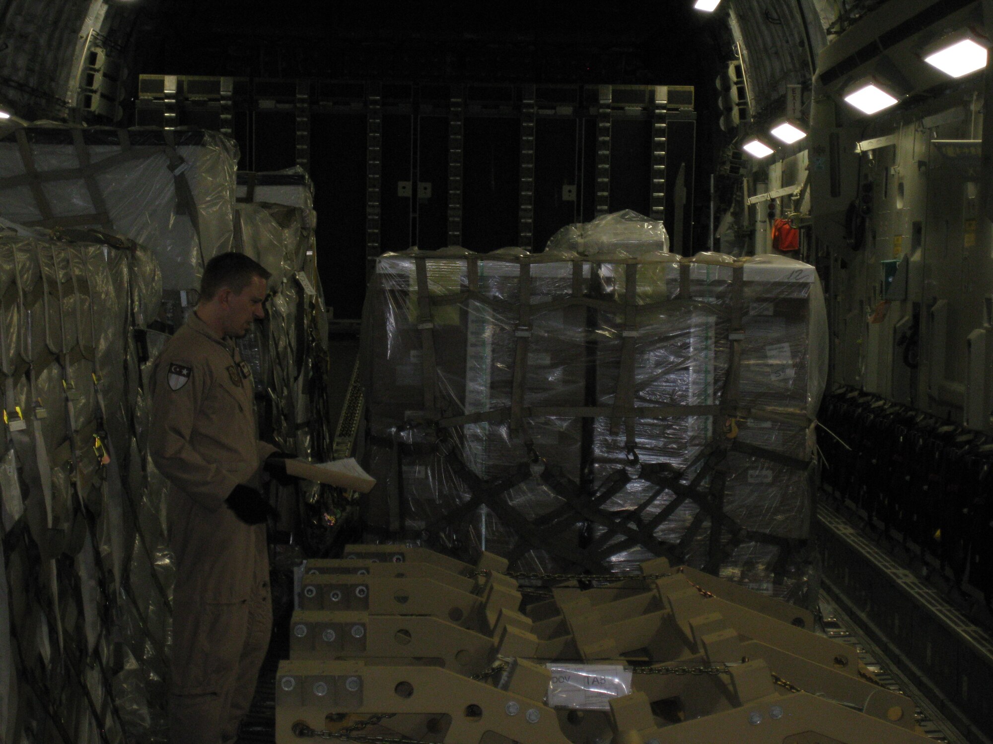 Tech. Sgt. Sean Arnold, 21st Airlift Squadron, inspects palletized cargo during a C-17 Globemaster III deployment at a base downrange. (U.S. Air Force photo)