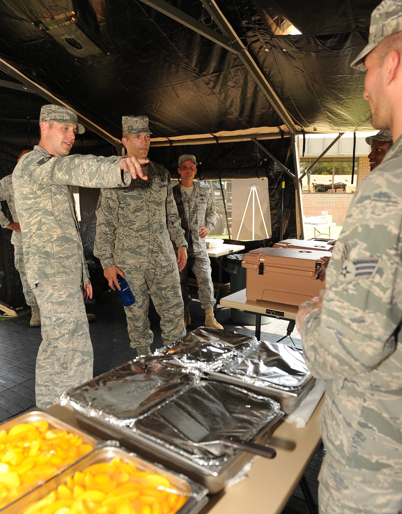 LANGLEY AIR FORCE BASE, Va. - Tech. Sgt. Ryan Hill, 633d Force Support Squadron unit deployment manager, shows  Chief Master Sgt. Martin Klukas, Air Combat Command command chief, and Chief Master Sgt. Charles Anderson, 633d Air Base Wing command chief, the food line of the Single Pallet Expeditionary Kitchen during a base tour Aug 10.  SPEK is a lightweight quick response kitchen capable of serving 550 personnel. It is best used in austere locations for up to 30 days. (U.S. Air Force photo/Senior Airman Gul Crockett) 

