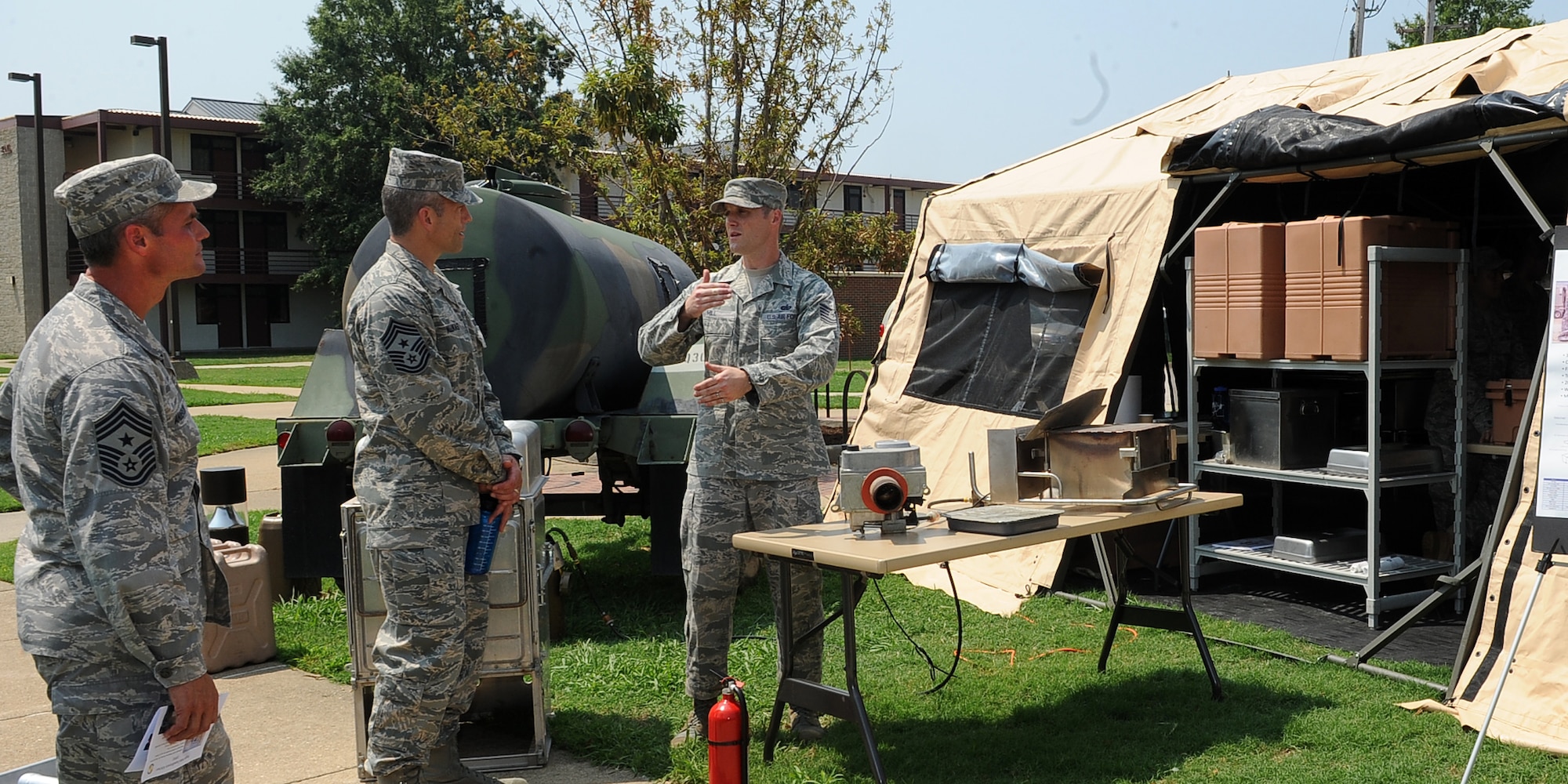 LANGLEY AIR FORCE BASE, Va. - Tech. Sgt. Ryan Hill, 633d Force Support Squadron unit deployment manager, explains to Chief Master Sgt. Martin Klukas, Air Combat Command command chief, and Chief Master Sgt. Charles Anderson, 633d Air Base Wing command chief, the Single Pallet Expeditionary Kitchen during a base tour Aug 10.  SPEK is a lightweight quick response kitchen capable of serving 550 personnel. It is best used in austere locations for up to 30 days. (U.S. Air Force photo/Senior Airman Gul Crockett) 

