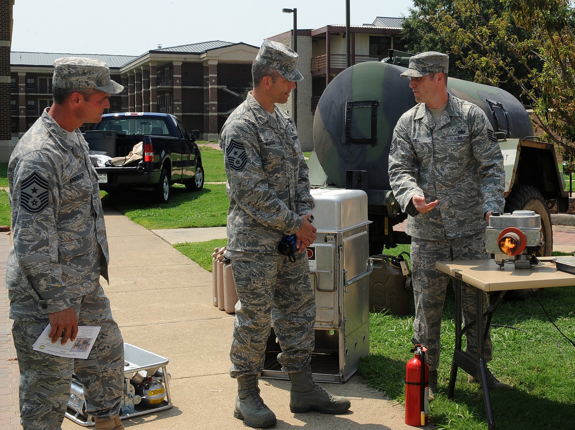 LANGLEY AIR FORCE BASE, Va. - Tech. Sgt. Ryan Hill, 633d Force Support Squadron unit deployment manager, shows Chief Master Sgt. Martin Klukas, Air Combat Command command chief, and Chief Master Sgt. Charles Anderson, 633d Air Base Wing command chief, the Babington Airtronic Burner for the Single Pallet Expeditionary Kitchen during a base tour Aug 10.  SPEK is a lightweight quick response kitchen capable of serving 550 personnel. It is best used in austere locations for up to 30 days. (U.S. Air Force photo/Senior Airman Gul Crockett) 