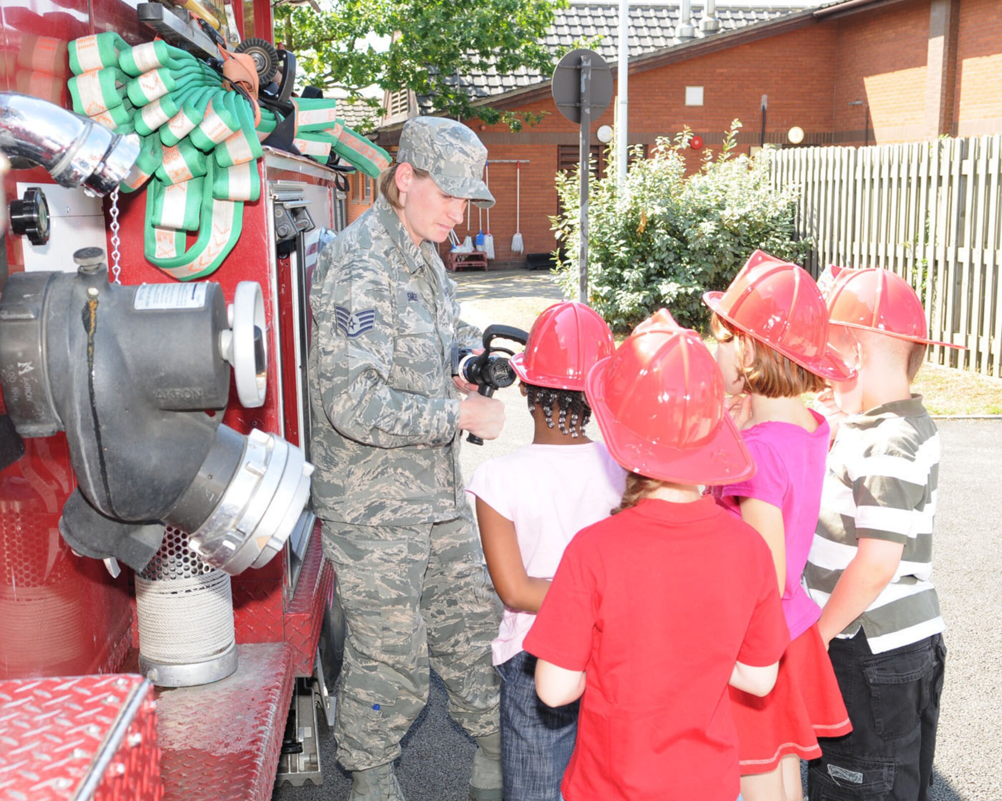 RAF MILDENHALL, Engalnd -- Staff Sgt. Jessica Smiley, 100th Civil Engineer Squadron Fire Department, shows children around a fire truck, and talks to them about the equipment used by the firefighters at a fire prevention event Aug. 9 at the youth center. (U.S. Air Force photo/Karen Abeyasekere)