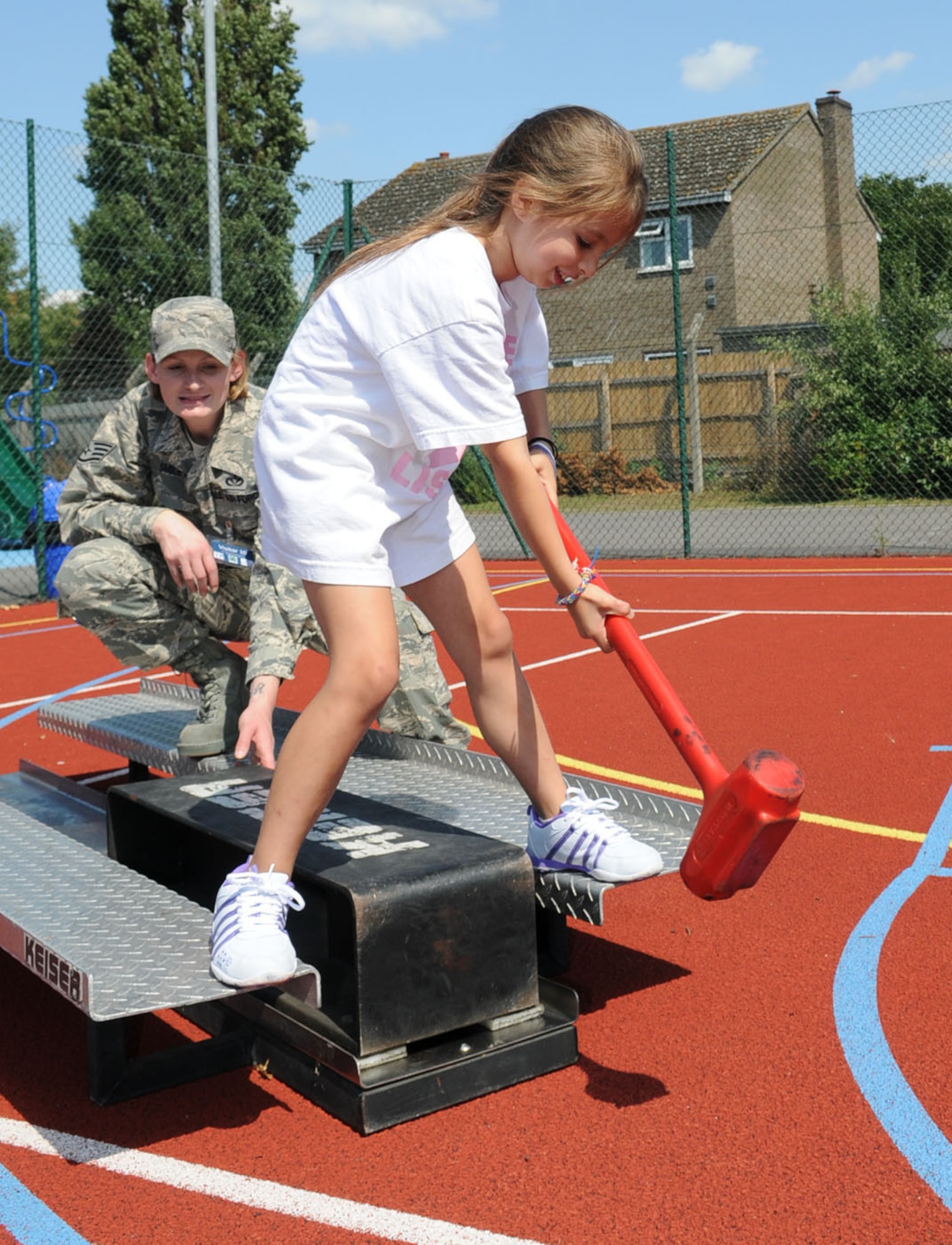 RAF MILDENHALL, Engalnd -- Rihana Grewal, 7, has a turn at hitting the Kaiser sled with a mallet as Staff Sgt. Jessica Smiley, 100th Civil Engineer Squadron Fire Department, stays close by to ensure she does it safely Aug. 9. The fire prevention office had an event at the youth center for children at summer camp, which included a fire safety room, fire muster, inflatable slide, looking around a fire truck, and a visit from Sparky the Fire Dog. (U.S. Air Force photo/Karen Abeyasekere)