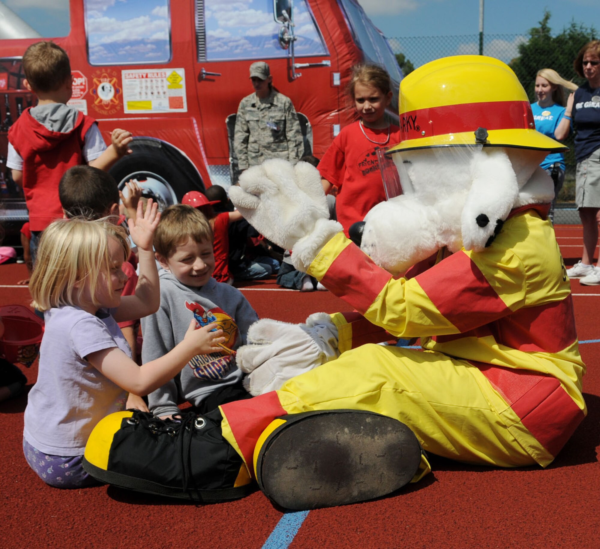 RAF MILDENHALL, Engalnd -- Abigail Humphrey (left), 5,  and Adrian Kranes, 5, play games with Sparky the Fire Dog at the fire prevention event Aug. 9 at the youth center. Firefighters from the 100th Civil Engineer Squadron Fire Department visited the children and taught them about fire safety and prevention through fun activities throughout the afternoon. (U.S. Air Force photo/Karen Abeyasekere)