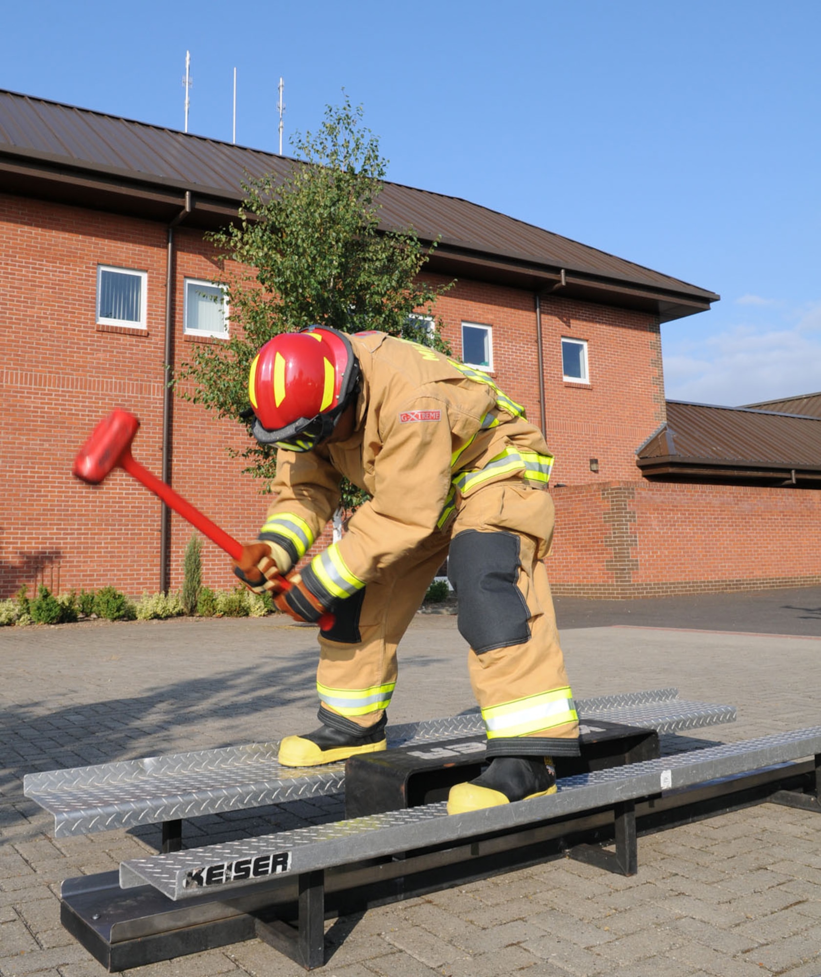 A firefighter from the 100th Civil Engineer Squadron Fire Department combat challenge team hits a 160-pound sled backwards with a mallet. This training is part of several events, performed by a team of six firefighters, for the Firefighter Combat Challenge World Challenge XIX competition in South Carolina in November. The entire competition must be performed in protective gear, including breathing apparatus and mask. (U.S. Air Force photo/Karen Abeyasekere)