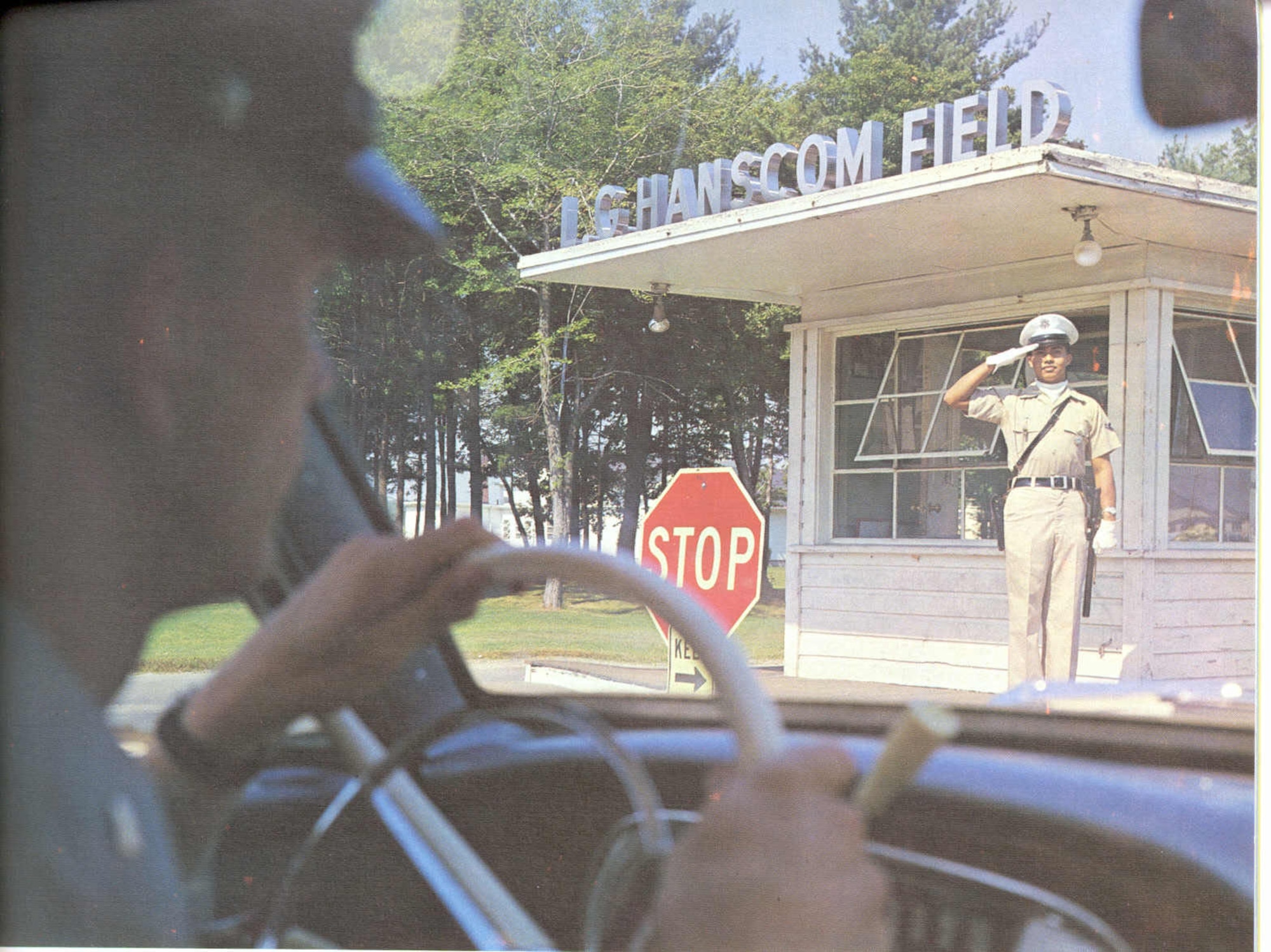 An Airman salutes as personnel drive on to Hanscom Field in 1966. (U.S. Air Force photo) 