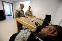 MINOT AIR FORCE BASE, N.D. -- Tech. Sgt. Lee Osberry, 5th Bomb Wing public affairs base visual information manager, documents Staff Sgt. Ryan Pfeifer, 791st Missile Security Forces Squadron convoy response force leader, as he explains a recovery and recapture exercise using a visual aid to Senior Airman Barrett Curlis, 791st MSFS convoy response force leader, during a convoy training mission here Aug. 12. (U.S. Air Force photo by Senior Airman Benjamin Stratton)