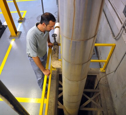 Stephen Honrath, Packaging and Crating Shop welder, peers down an 18-foot deep steam pit which was a fall hazard before his team constructed a safety rail around it. The rail was one of many improvements the team made to become a Gold Site.  (U.S. Air Force photo by Tommie Horton)

