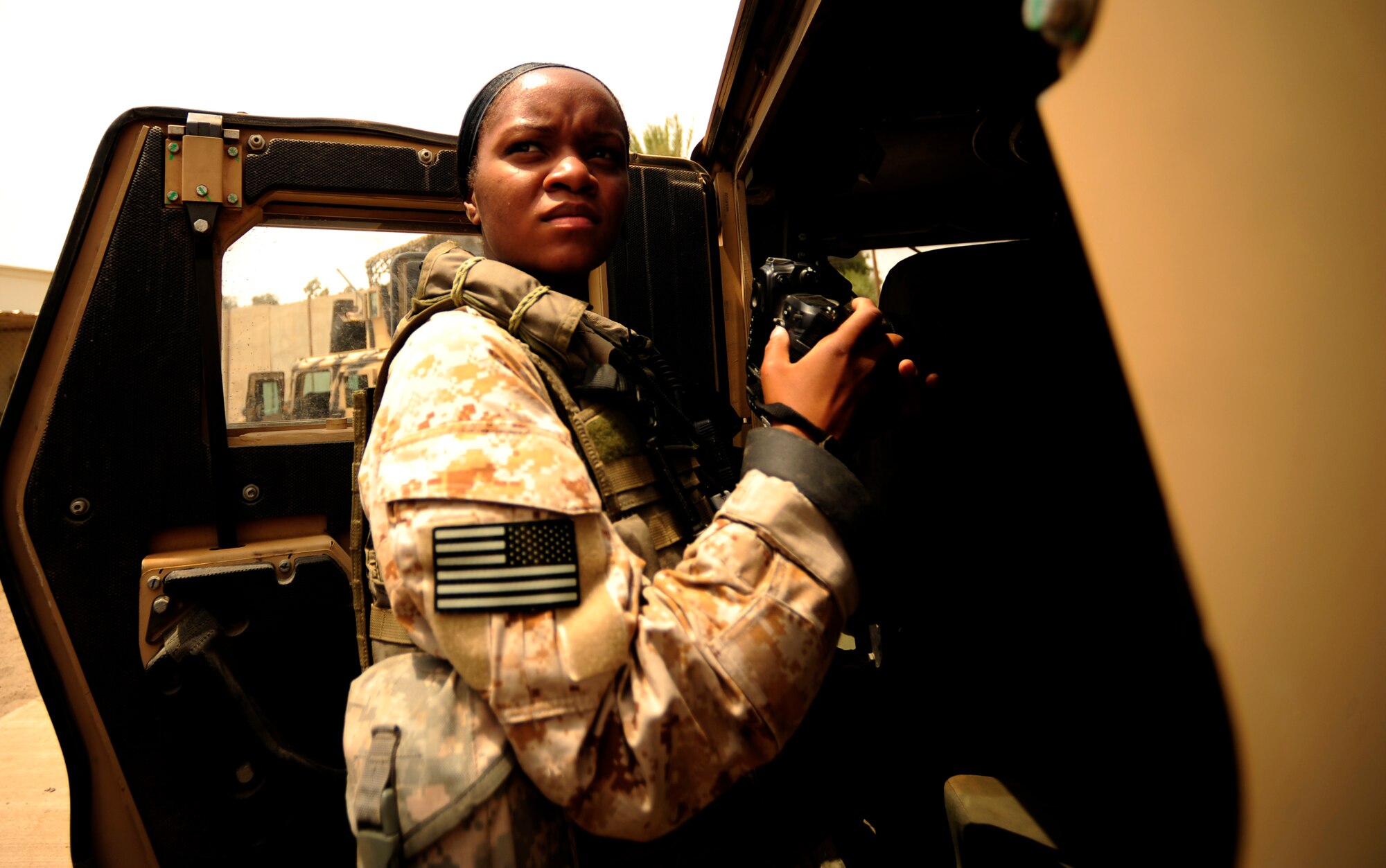 U.S. Air Force Senior Airman Asha McMakin, a combat photographer assigned to the 1st Combat Camera Squadron, looks over at another vehicle while documenting teams gearing up for key leader engagement mission at Ramadi, Iraq on Aug. 2, 2010. SrA McMakin is attached to an Army Civil Affairs team while deployed in support of Operation Iraqi Freedom.
(U.S. Air Force photo by Staff Sgt. Andy M. Kin / Released)