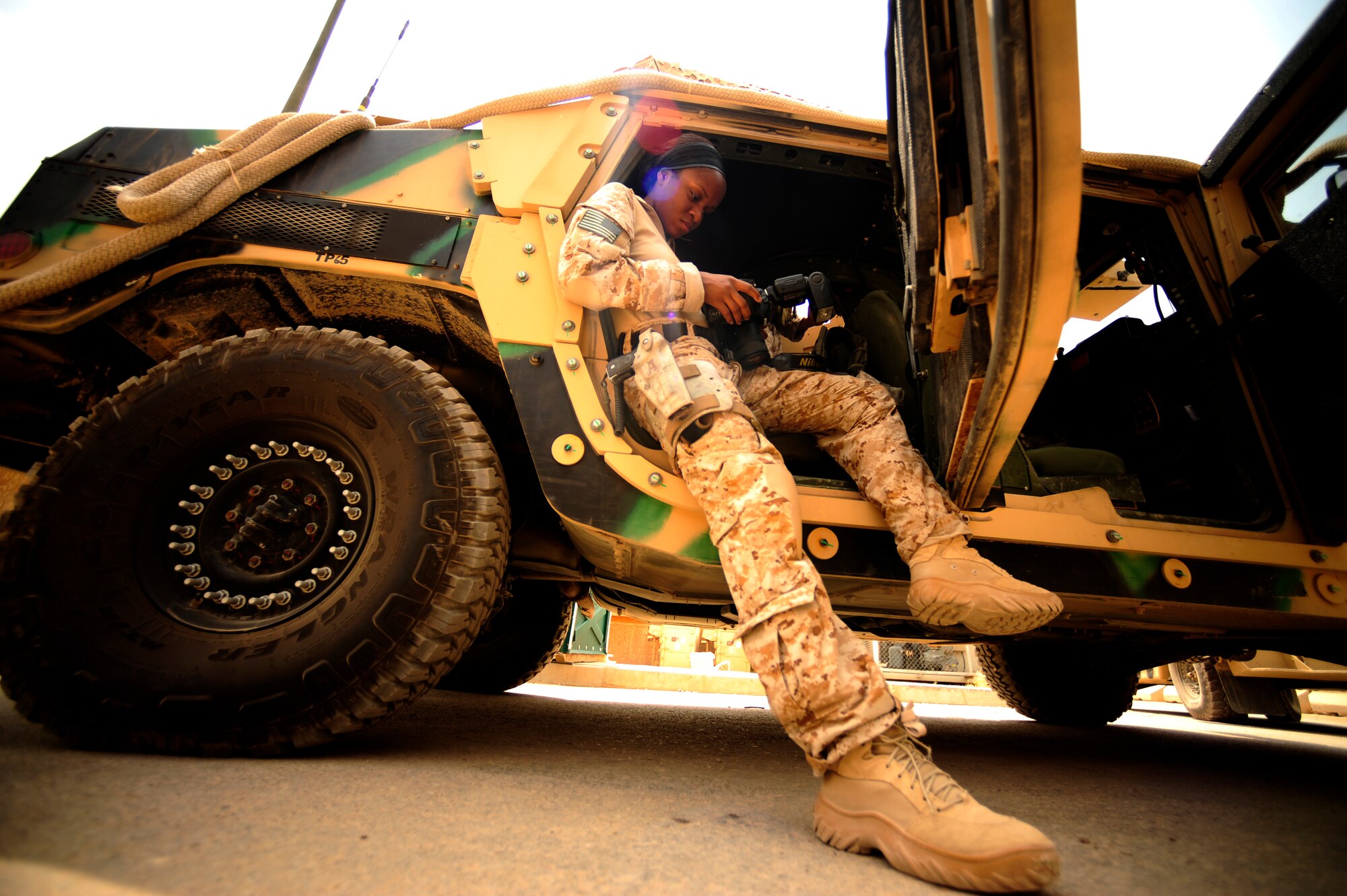 U.S. Air Force Senior Airman Asha McMakin, a combat photographer assigned to the 1st Combat Camera Squadron, hangs out of a High Mobility Multipurpose Wheeled Vehicle (HMMWV) while checking her camera prior to a key leader engagement mission at Ramadi, Iraq on Aug. 2, 2010. SrA McMakin is attached to an Army Civil Affairs team while deployed in support of Operation Iraqi Freedom.
(U.S. Air Force photo by Staff Sgt. Andy M. Kin / Released)