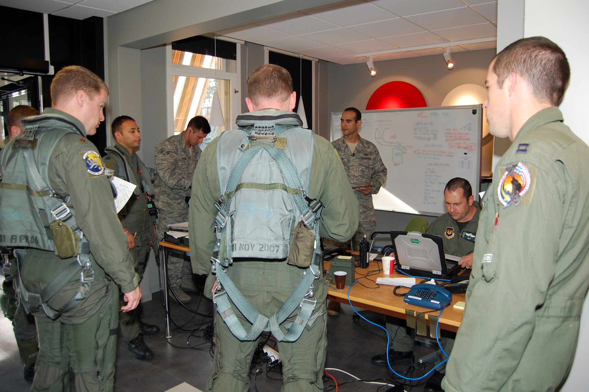 Pilots of the 555th Fighter Squadron receive a pre mission brief before heading out to the flightline Aug. 6, 2010 at Kallax Air Base, Sweden. The 555th FS and 31st Aircraft Maintenance Squadron conducted more than 180 air-to-air and air-to-ground missions during a two week exercise at the air base in which they worked alongside the Swedish air force's Norrbotten Wing. (U.S. Air Force photo illustration by Tech. Sgt. Lindsey Maurice/Released)