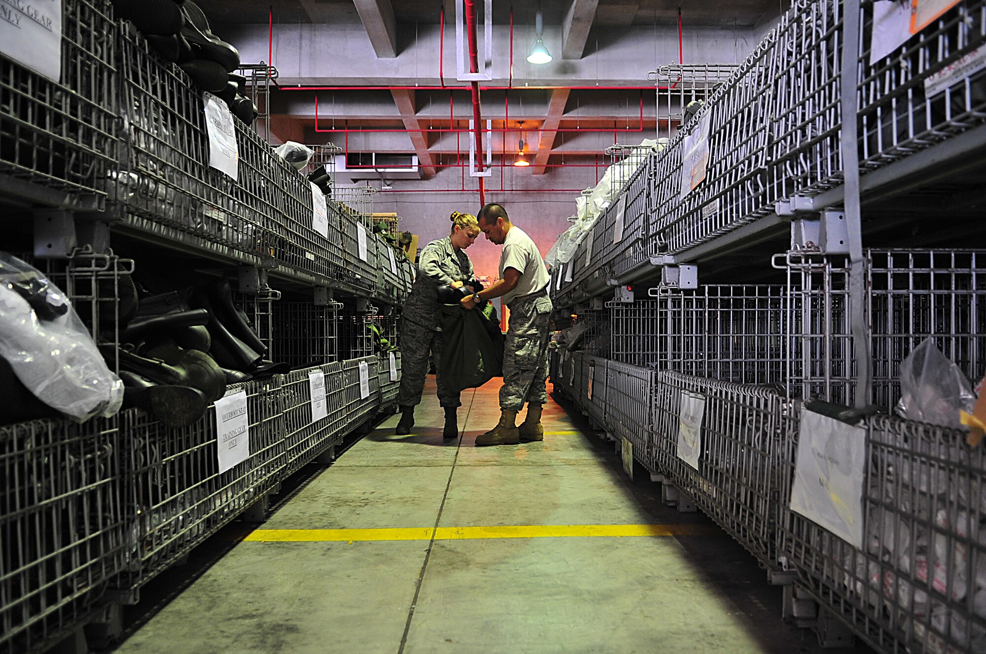 Airman 1st Class Jacquelin Herrera (left) and Tech. Sgt. Rafael Ortega, both members of the 18th Logistics Readiness Squadron, pack mobility bags at Kadena's individual protective equipment warehouse Aug. 15, 2010, in preparation for the upcoming local operational readiness exercise. The IPE clerks issue mobility bags to Airmen for LOREs and real-world deployments. (U.S. Air Force photo/Staff Sgt. Alesia Goosic)