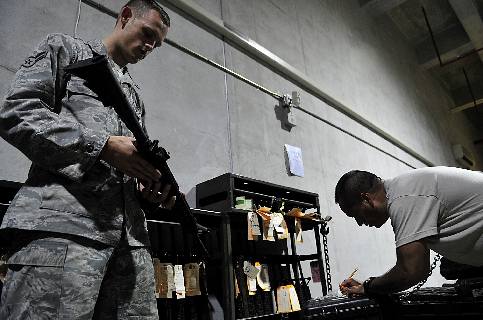 Airman 1st Class Jeffrey Jones (left) verifies serial numbers from an M-4 with Tech. Sgt. Rafael Ortega at the individual protective equipment warehouse Aug. 15, 2010. Both Airmen are members of the 18th Logistics Readiness Squadron and are inventorying weapons in preparation for the upcoming operational readiness exercise.  (U.S. Air Force photo/Staff Sgt. Alesia Goosic)