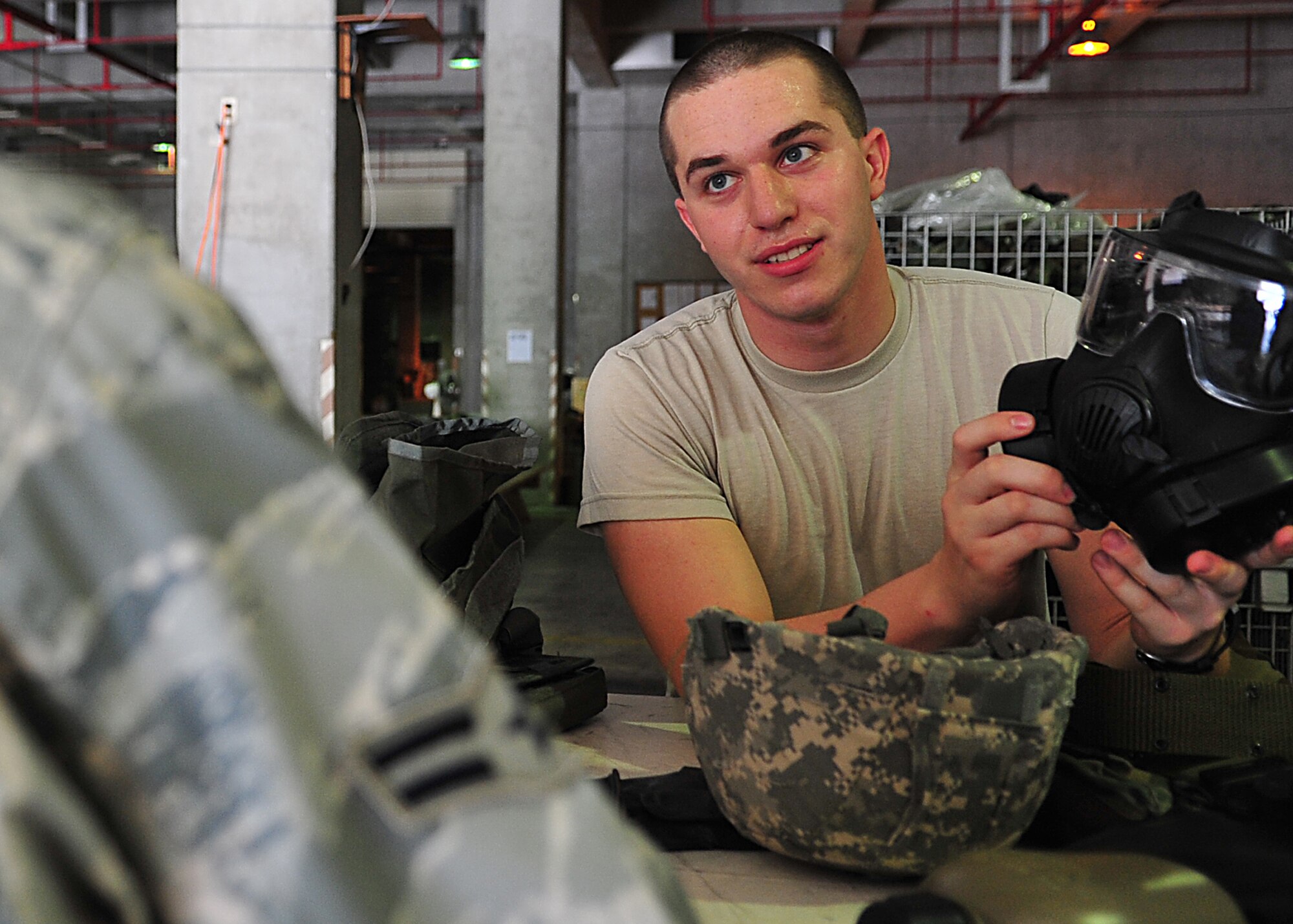 Airman 1st Class Tyler Matthews, an individual protective equipment clerk with the 18th Logistics Readiness Squadron, explains the proper use of a gas mask to a customer at Kadena's IPE warehouse Aug. 15, 2010. Airmen can get necessary mobility issue items at the warehouse prior to the upcoming operational readiness exercise. (U.S. Air Force photo/Staff Sgt. Alesia Goosic)