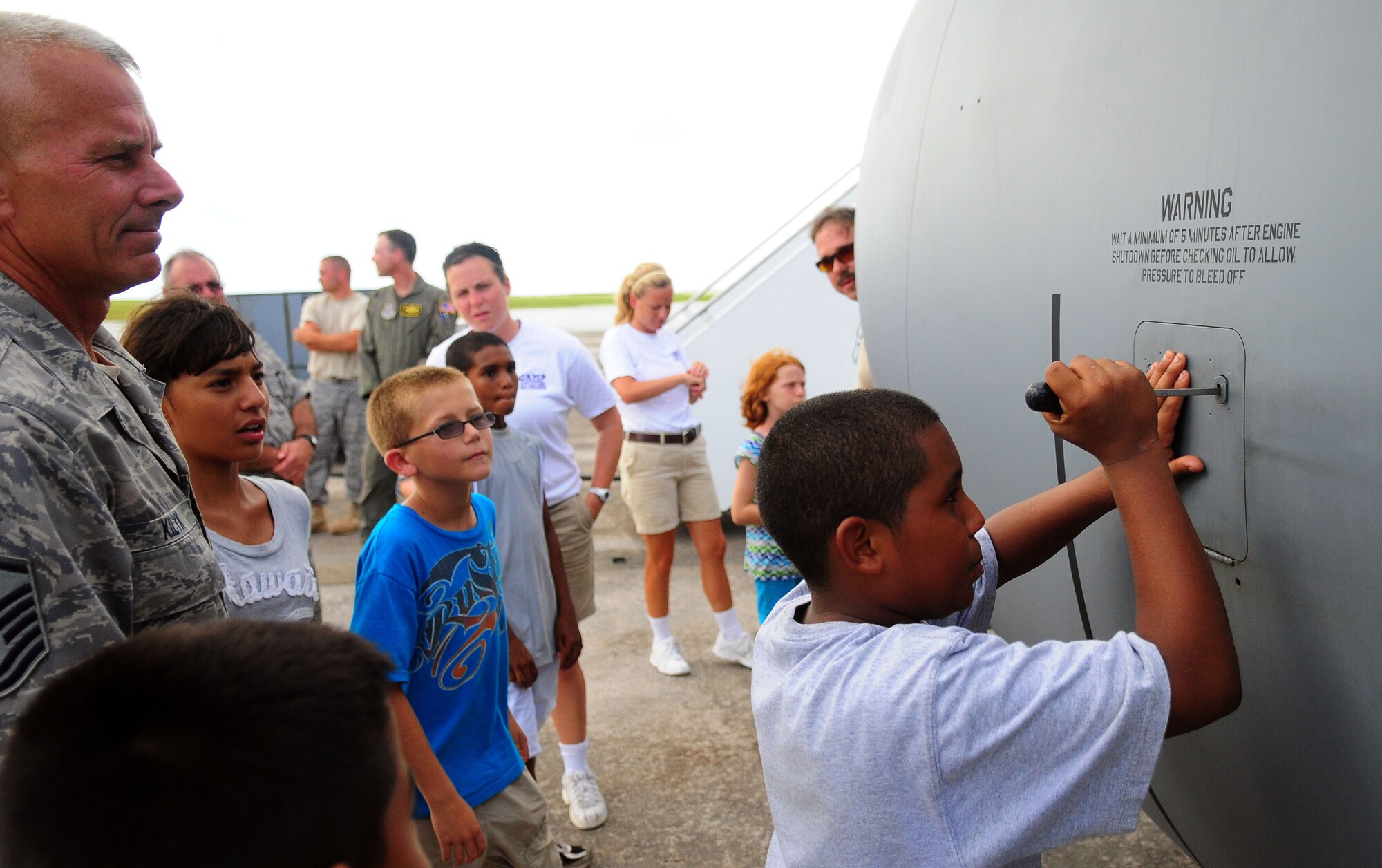 ANDERSEN AIR FORCE BASE, Guam - Master Sgt. Ted Kilyk, crew chief 171st Air National Guard, instructs an Operation Purple Camp attendee how to open the oil reservoir of a KC-135 Stratotanker here Aug. 5. The KC-135 was on static display and camp-goers were given a tour inside and out of the tanker. (U.S. Air Force photo by Airman Julian North)