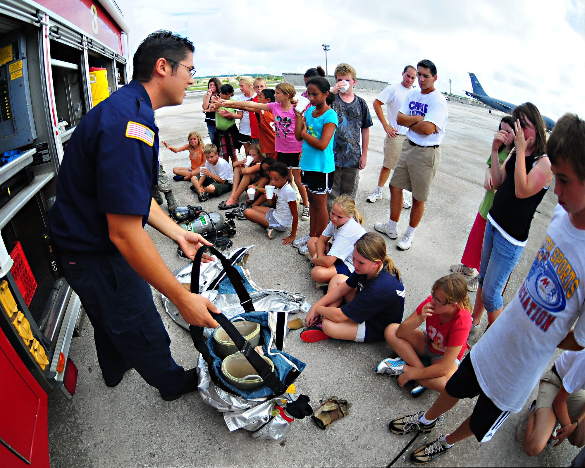 ANDERSEN AIR FORCE BASE, Guam - Lieutenant Michael Arzabal, Andersen Fire and Energy Services, explains the fire protection suits worn by the firefighters to a group of Operation Purple Camp attendees here Aug. 5. Operation Purple Camp is a summer camp open to children of servicemembers from every branch, active, guard or reserve, and is designed to help the participants better understand their parent's lives through military themed activities. (U.S. Air Force photo by Airman Julian North) 