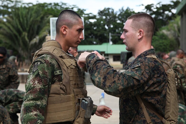 Lance Cpl. Adam D. Fahnestock, native of Carleton, Mich., and radio technician with Company A, 2nd Assault Amphibian Battalion, Ground Combat Element of Special-Purpose Marine Air-Ground Task Force Continuing Promise 2010, assists a Colombian Marine put on U.S. Marine personal protective equipment at Colombian Marine Corps Training Base Covenas in Colombia, Aug. 14, 2010. Marines from USS Iwo Jima conducted subject matter expert exchanges with Colombian Marines Aug. 9-17 in support of Operation Continuing Promise 2010.