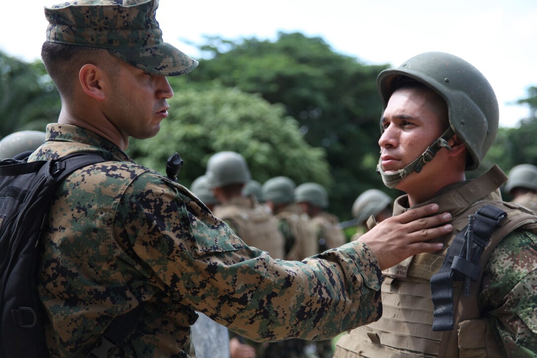Cpl. Alejandro Melendez, native of San Juan, Puerto Rico, and crew chief of Company A, 2nd Assault Amphibian Battalion, Ground Combat Element of Special-Purpose Marine Air-Ground Task Force Continuing Promise 2010, explains to a Colombian Marine why U.S. Marines wear a throat protector on their personal protective equipment during non-lethal weapons training at Colombian Marine Corps Training Base Covenas in Colombia, Aug. 14, 2010. Marines from USS Iwo Jima conducted subject matter expert exchanges with Colombian Marines Aug. 9-17 in support of Operation Continuing Promise 2010.