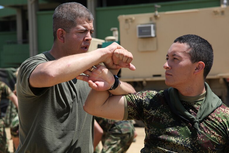 Staff Sgt. Gabriel Delarosa, native of Holland, Mich., and section leader of Company A, 2nd Assault Amphibian Battalion, Ground Combat Element of Special-Purpose Marine Air-Ground Task Force Continuing Promise 2010, shows a Colombian Marine a takedown technique during a non-lethal weapons training class at Colombian Marine Corps Training Base Covenas in Colombia, Aug. 14, 2010. Marines from USS Iwo Jima conducted subject matter expert exchanges with Colombian Marines Aug. 9-17 in support of Operation Continuing Promise 2010.